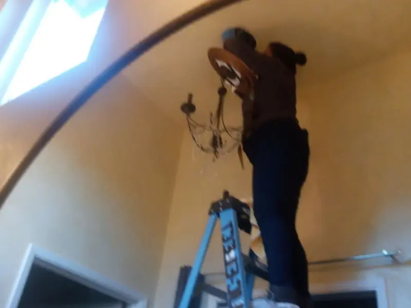 Electrician installing a chandelier in a Meridian residence